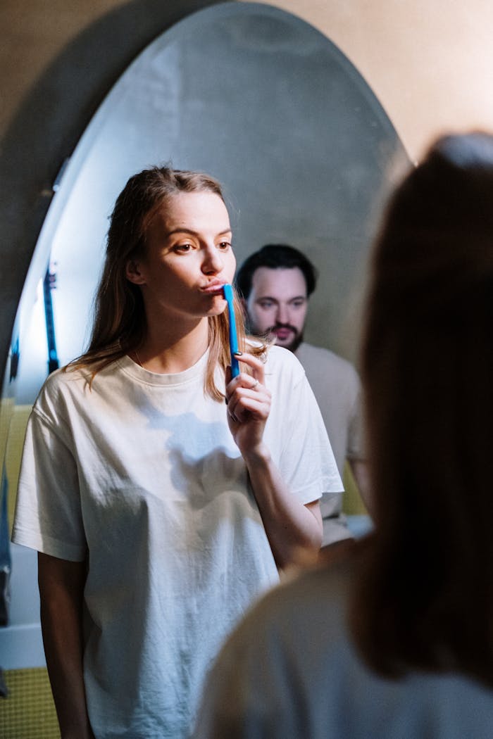A couple practices dental hygiene together at home, reflecting a cozy morning routine.