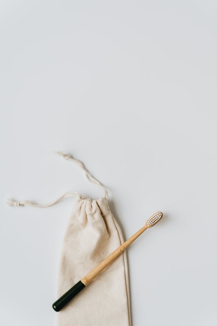 A minimalist bamboo toothbrush with a cotton bag on a light background, ideal for eco-conscious consumers.