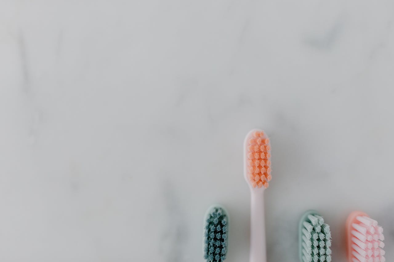 A clean and simple flat lay of four colorful toothbrushes on a marble surface.