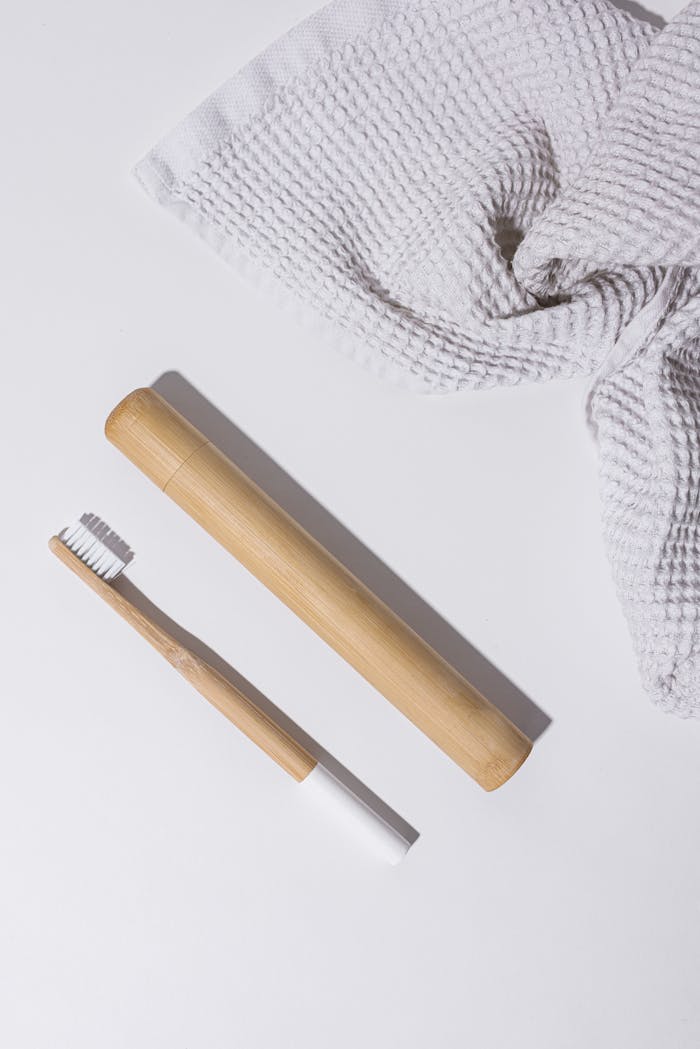 Minimalist bamboo toothbrush and face towel in bright flat lay for eco-conscious living.